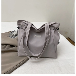 Detail of grey canvas tote bag with drawstring closure and fashion label on front