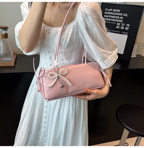Detail of pink shoulder bag with pearl bow, metal heart charm and lace strap accents