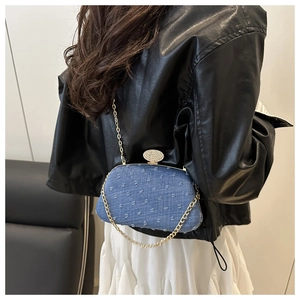 Blue denim evening clutch with gold metal frame and crystal clasp on model with leather jacket