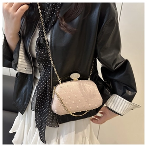 Detail of light pink textured handbag with elegant gold chain and diamond oval clasp