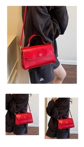 Macro view of a red leather crossbody bag featuring a golden double B metal buckle and flap