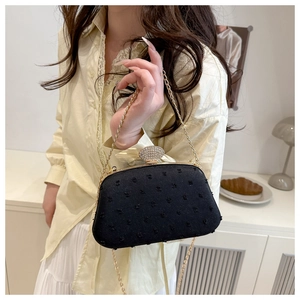 Detail of black fabric evening bag with sparkling rhinestone buckle and gold chain strap
