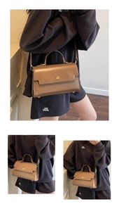 Detail of brown leather handbag with gold butterfly clasp and adjustable strap