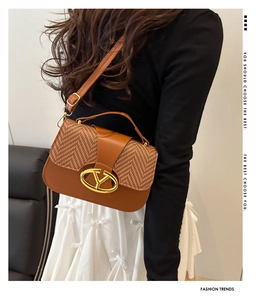Fashion brown saddle bag with woven texture flap and golden metal clasp on a model