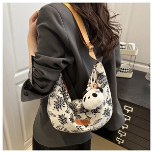 Dettaglio borsa a mezzaluna in tela floreale vintage con ciondolo a panda