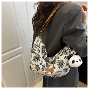 Dettaglio borsa hobo in tela floreale con tracolla in pelle e ciondolo panda di peluche