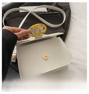 Detailed macro view of the white leather saddle bag showing the golden magnetic closure