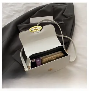 Internal capacity of white rectangular shoulder bag with items on dark grey suit fabric
