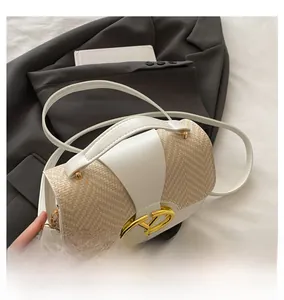 Detail of white leather and straw saddle bag featuring a gold V-shaped metal buckle clasp