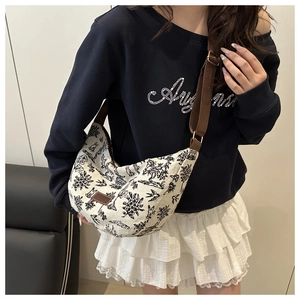Borsa a mezzaluna in tela floreale indossata da modella con tracolla marrone