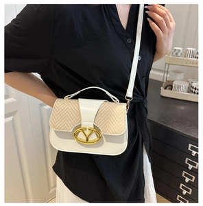 Detail of a beige saddle bag with woven texture and gold V-logo buckle on crossbody strap