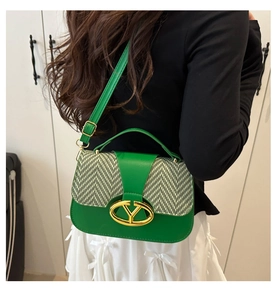 Detail of green leather saddle bag with woven flap and gold V-shaped metal logo buckle