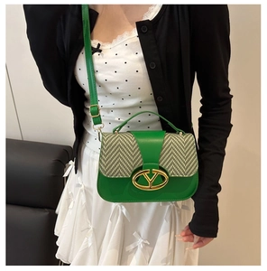 Close-up of green saddle bag featuring herringbone fabric and a gold metal Y-shaped buckle