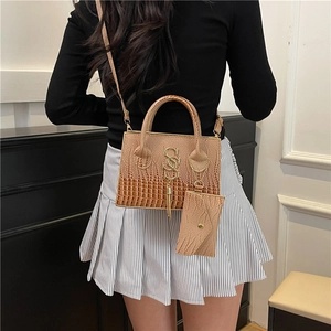 Brown crocodile embossed tote bag with letter logo and tassel shown on model