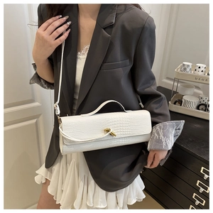 Detailed view of white crocodile pattern crossbody bag with golden knot clasp and PU texture