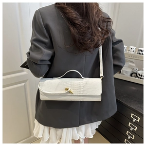 Détail du sac cylindre blanc à motif crocodile avec un fermoir en métal doré torsadé