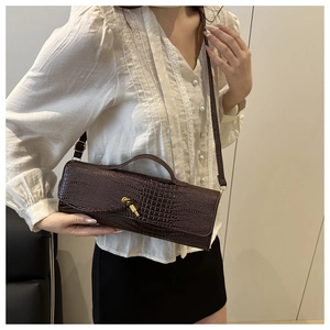 Détail du sac à main marron foncé texture crocodile avec fermoir doré et bandoulière