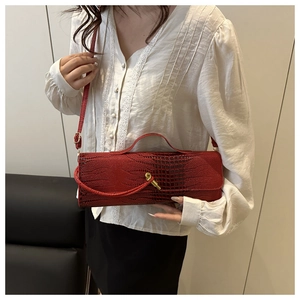 Detail of red crocodile texture handbag with golden knot buckle on white shirt