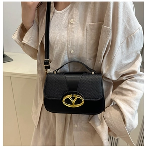 Chic black crossbody bag detail showing leather texture and gold oval logo clasp