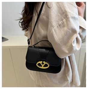 Close-up of black textured leather bag with luxury gold Y-shaped metal clasp and strap