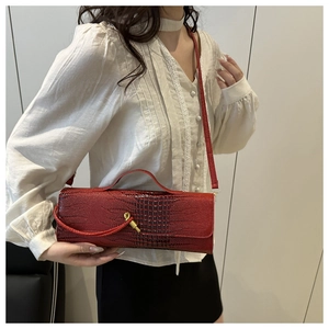 Detail of burgundy crocodile pattern handbag with gold twist lock and elegant texture