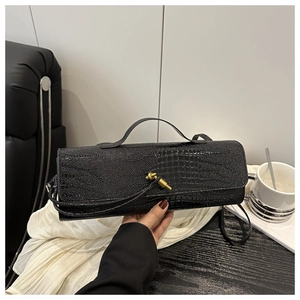 Close-up of black crocodile pattern leather handbag with gold twist lock and top handle