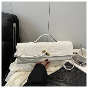 Close-up of white crocodile pattern bag featuring a gold twist lock and sleek top handle