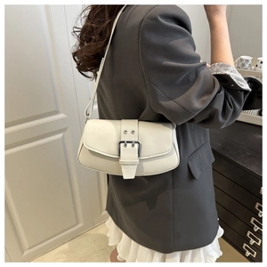 Detail of minimalist beige faux leather shoulder bag with large silver buckle for women
