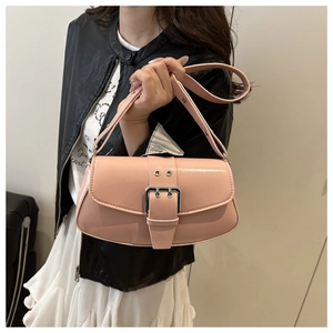 Close-up of a pink glossy leather underarm bag with silver buckle worn by a model