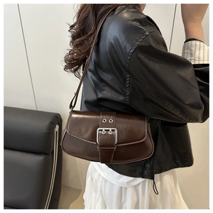 Close-up of brown leather saddle bag with silver metal buckle on a shoulder