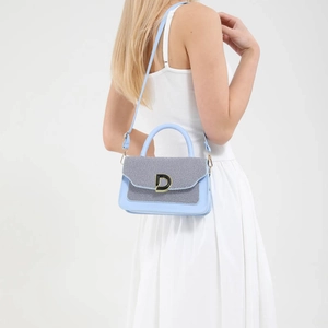 Blue woven crossbody handbag with gold D-buckle and top handle shown on a model