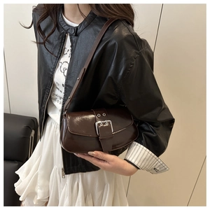 Detail of vintage brown leather underarm bag with polished silver buckle and sleek texture