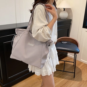 Minimalist grey nylon tote bag with Fashion patch and drawstring details in a lifestyle setting