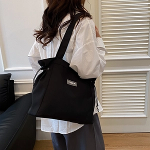 Minimalist black canvas tote bag with drawstring closure and silver Fashion label accent