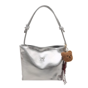 Silberne Metallic-Beuteltasche mit Metallschleife und braunem Plüschbär-Anhänger
