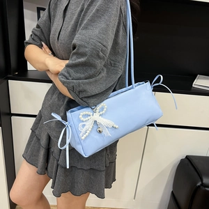 Light blue underarm bag with lace bow and pearl charm shown on model