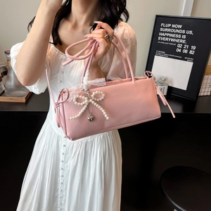 Pink rectangular shoulder bag with pearl bow and lace ribbons shown on a model