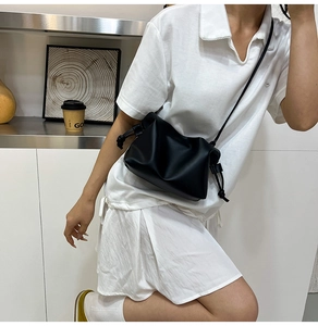 Detailed close-up of a black pleated bucket bag with soft drawstring closure and strap
