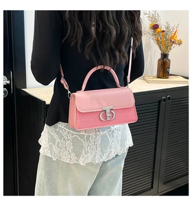Close-up of pink leather crossbody bag with woven texture and silver metal twist lock
