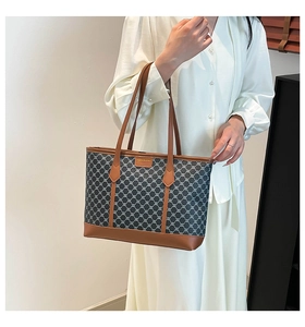 Detail of vintage geometric canvas tote bag with brown leather trim and metal label