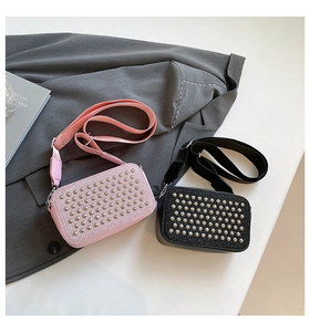Flat lay of pink and black crossbody bags with silver rivets on a grey suit jacket
