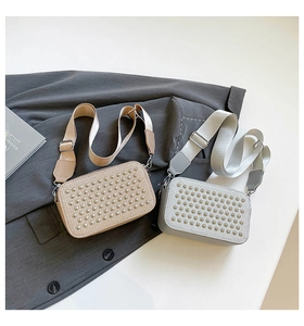 Detail of khaki and grey crossbody bags with metallic studs and wide fabric straps