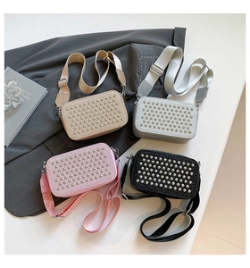 Flat lay of shimmering crossbody camera bags with metal studs and wide woven straps