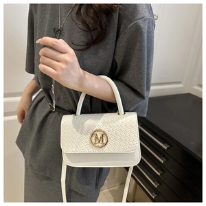 Détail du sac bandoulière blanc avec texture tressée et boucle métallique dorée lettre M