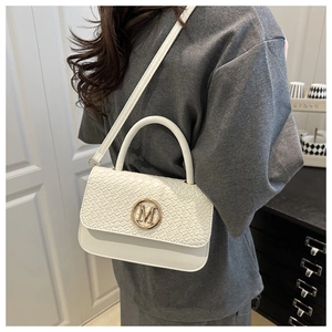 Photo de style d'un sac bandoulière blanc à texture tissée avec boucle dorée en M