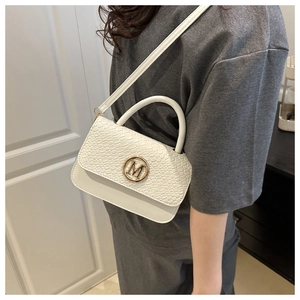 Detail view of white crossbody bag with crocodile texture flap and gold M logo