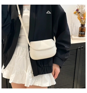 Detailed view of a white minimalist saddle bag with adjustable strap on a model
