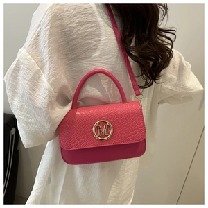 Détail du sac à main rose rouge avec rabat tissé et logo M doré sur le devant