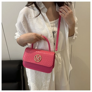 Sac à main rose fuchsia à motif tressé porté par un mannequin pour illustrer la taille