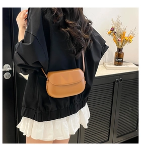 Caramel brown leather crossbody half-moon bag shown on a model for scale and style